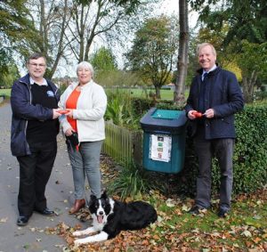 Dog owner Christine is handed a dog bag dispenser from Chair of Boston Big Local